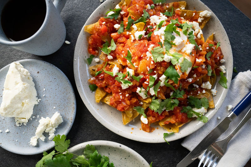 Plate of shakaquiles, topped with cilantro and feta cheese