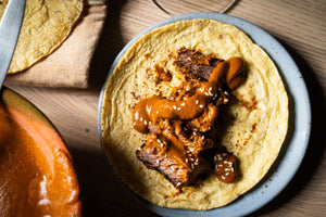A taco of short rib with mole on a plate