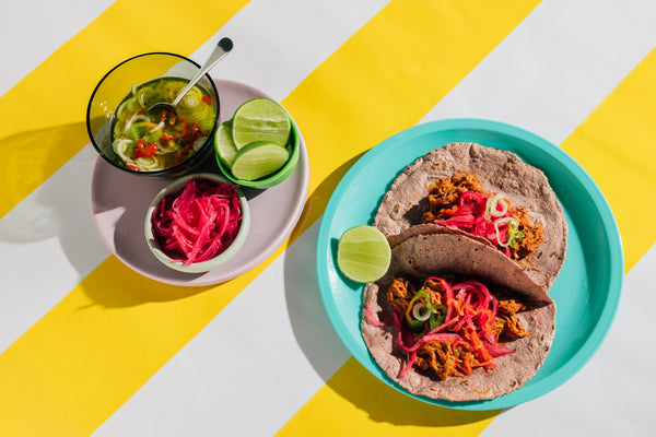 A plate of tacos with a side of garnishes
