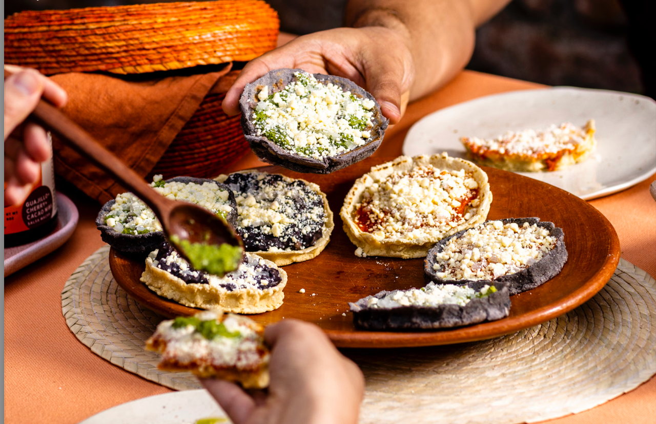 A plate of sopes being topped with salsa