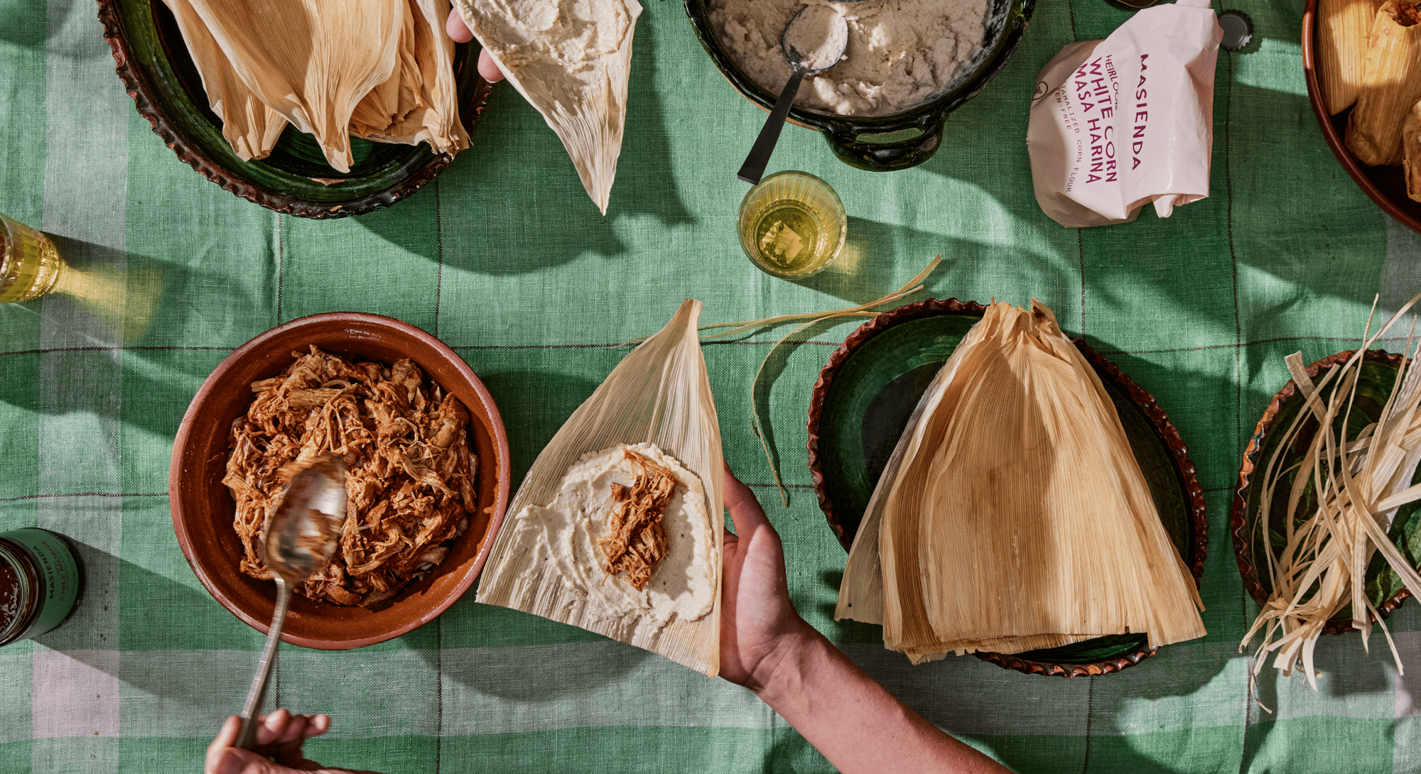 Tamalada preparada - Una mesa de hojas de maíz rellenas de pollo