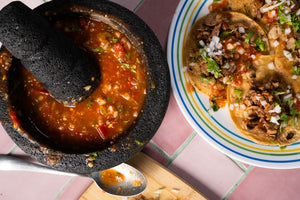 Salsa borracha en un molcajete, junto a un plato de tacos