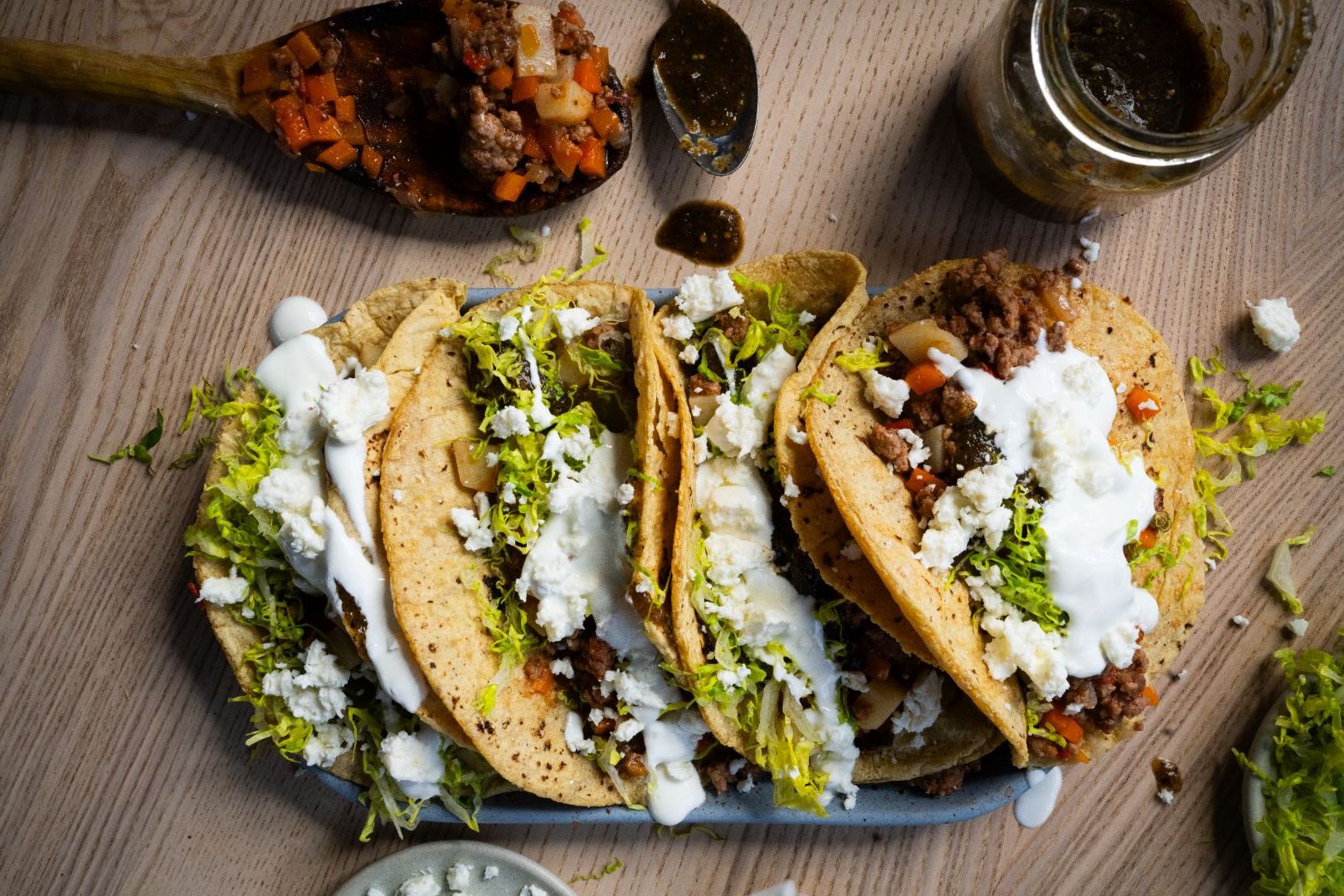 Plato de tacos de picadillos con lechuga, crema agria, queso fresco y salsa