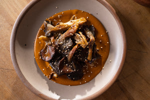 A plate with mole topped with mushrooms and sesame seeds