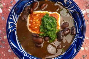 Bowl of brothy beans with cheese and chimichurri