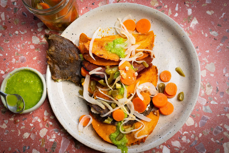 plate of tacos de canasta topped with pickled jalapeños and carrots, and salsa