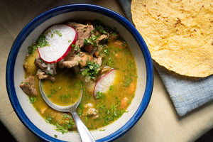 Bowl of carne en su jugo, garnished with radishes, cilantro and paired with freshly made tortillas