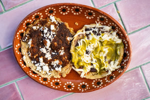Memelas on a plate with frijoles and queso topped with salsa