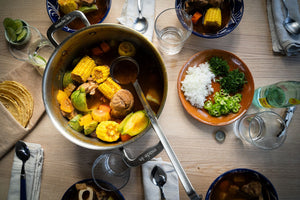 Pot of mole de olla with garnishes and fresh tortillas