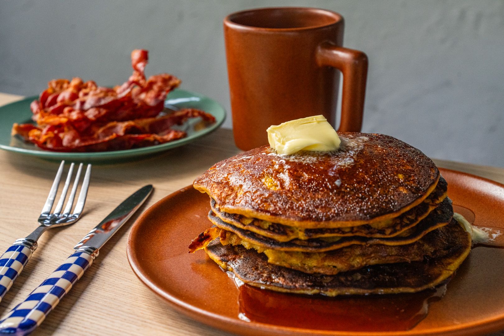 Plate of pancakes with a side of bacon and coffee