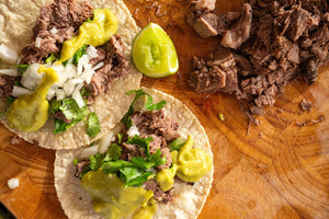 Tacos de Lengua topped with onion, cilantro, and avocado salsa