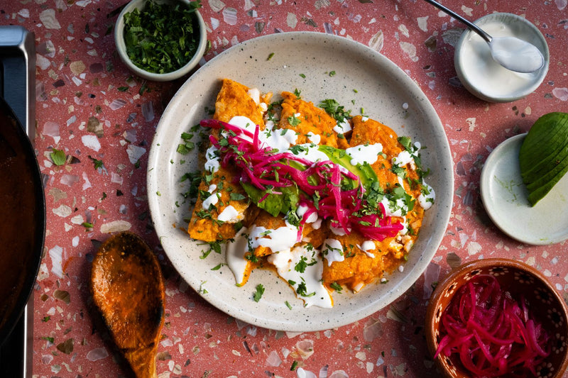 Plato de entomatadas con crema, cebolla morada encurtida y cilantro 