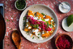Plate of entomatadas topped with crema, pickled red onions, and cilantro 