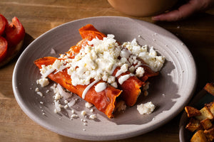 Plate of enchiladas with crumbled queso and crema