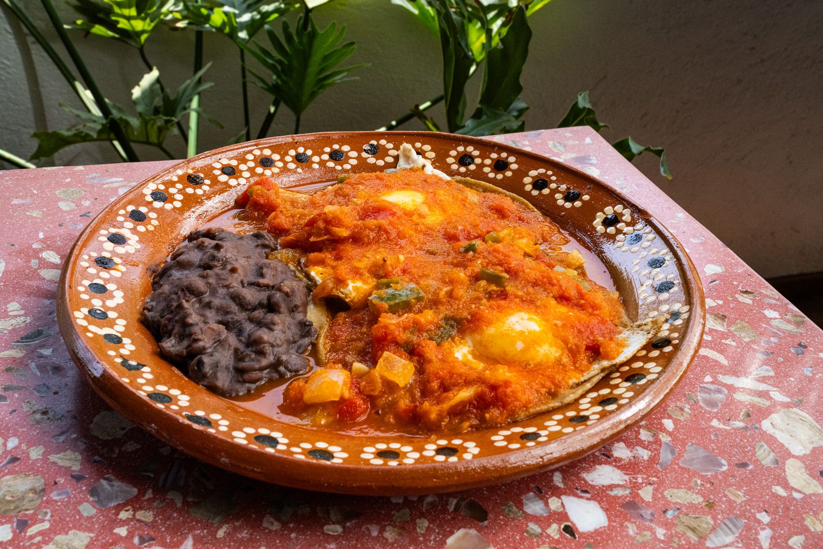 Un plato con huevos rancheros y frijoles