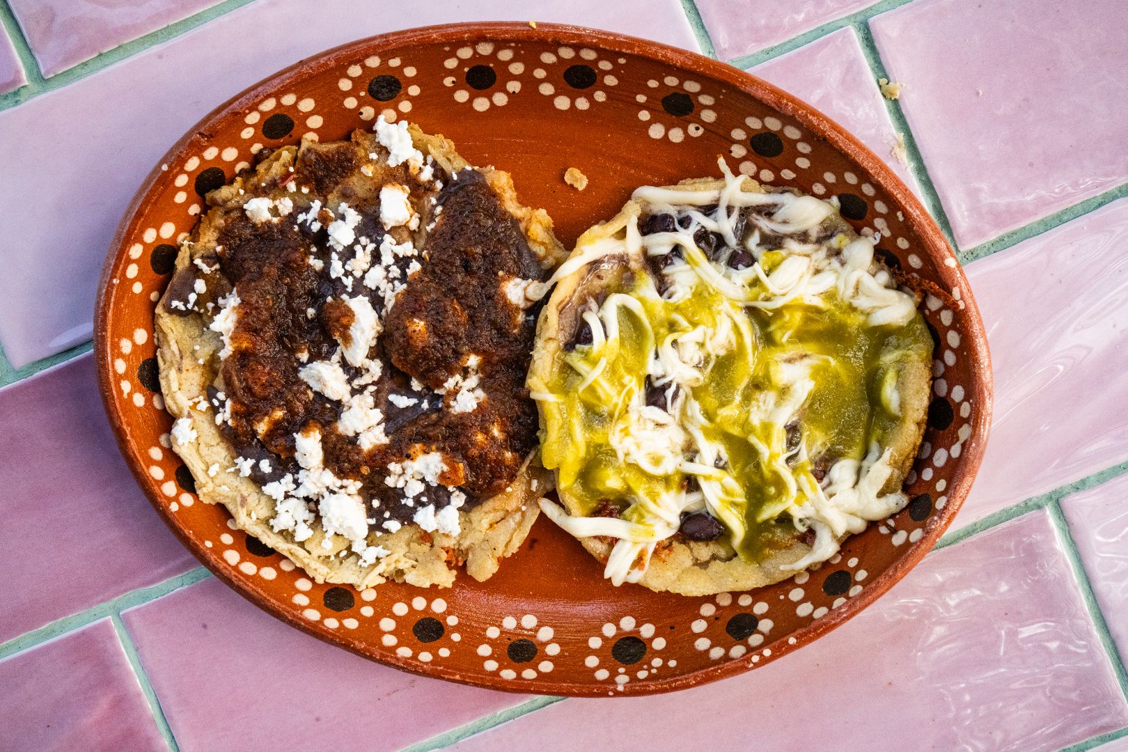 Memelas en plato con frijoles y queso bañadas con salsa