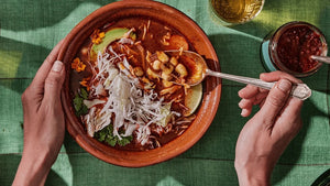 Tazón de pozole rojo con repollo, aguacate, cilantro, cebolla y rábanos